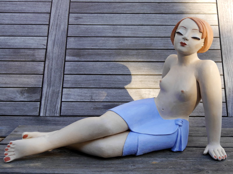 Sitzende Gartenfigur auf einer Bank